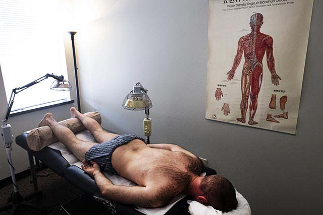  Adam lays on an acupuncture office. Adam doesn't take medication for his physical injuries or his PTSD. Instead, he finds acupuncture to be helpful in his pain management.